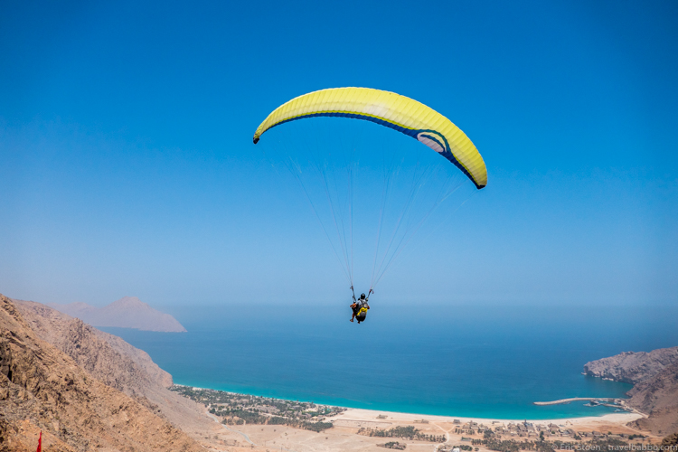 Around the world with kids - My daughter paragliding into the Six Senses Zighy Bay