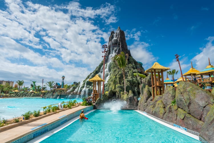 Volcano Bay: A person enters the splash pool from the Ko'okiri Body Plunge. You can see the transparent slide towards the top of the volcano. 